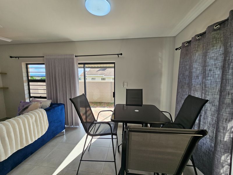 Open plan living and dining area featuring tiled flooring, large sliding glass doors leading to the patio, and neutral wall finishes.