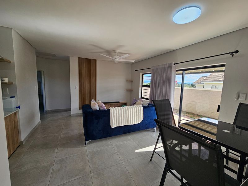 Open plan living area featuring tiled flooring, a ceiling fan, and large sliding glass doors leading to an outdoor patio.