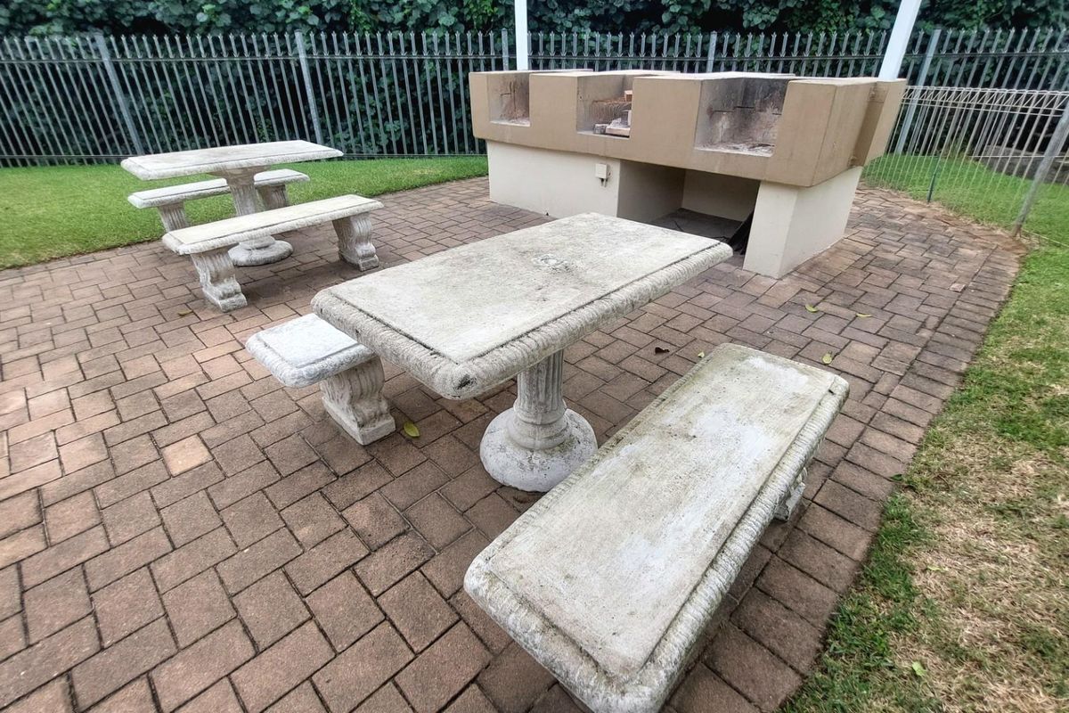 Outdoor communal area featuring a built-in brick braai and paved patio space, suitable for social gatherings.