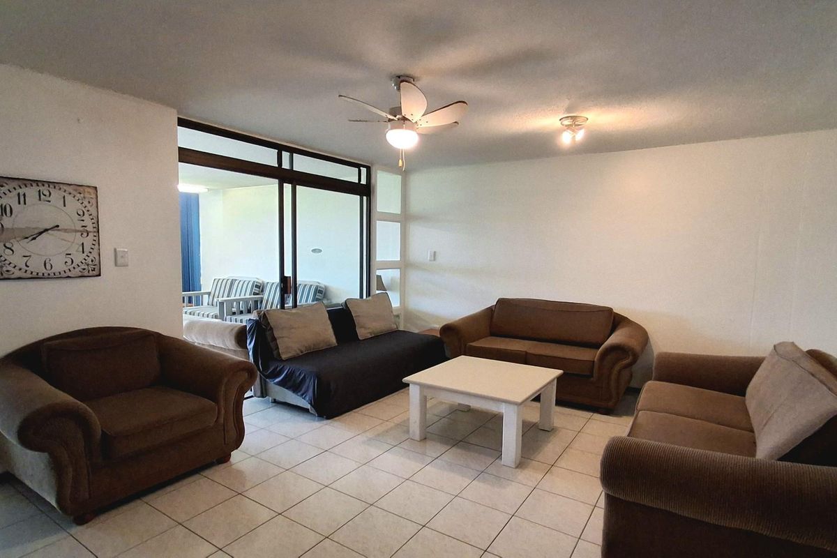 Spacious living area featuring tiled flooring, a ceiling fan, and large sliding glass doors providing access to an adjoining balcony space.