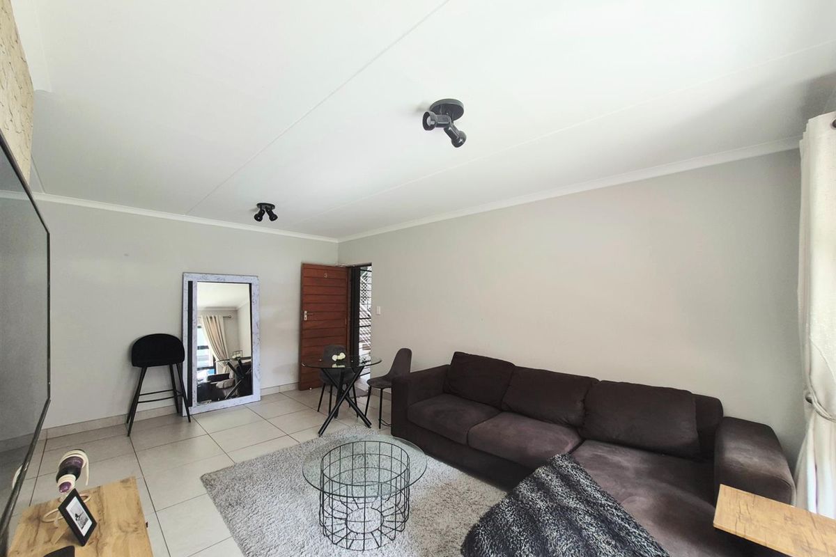 A spacious living area featuring neutral tiled flooring, modern spotlight fixtures, and a clean, open-plan layout suitable for comfortable daily living.