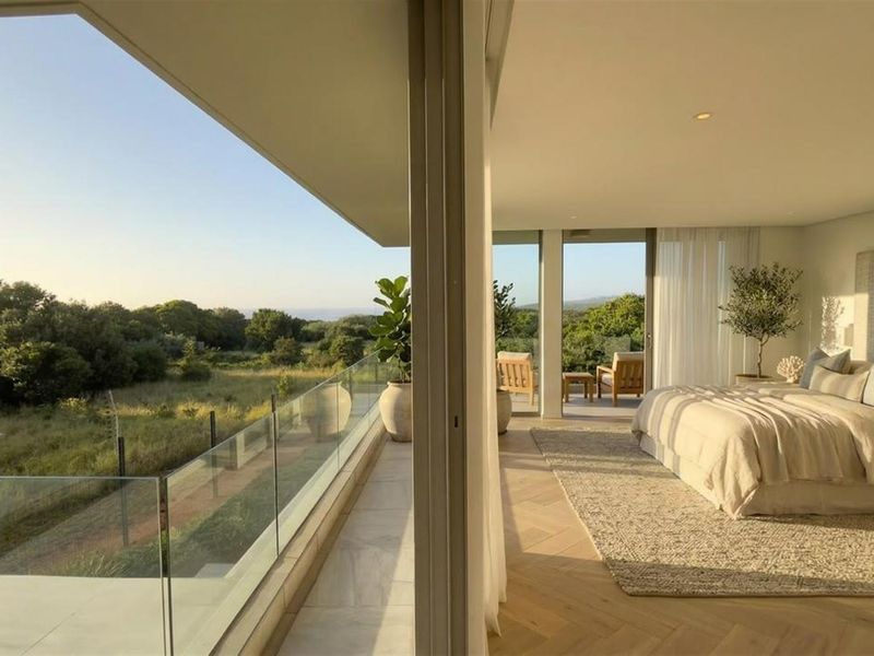 Spacious bedroom featuring herringbone timber flooring and large sliding glass doors opening onto a private balcony with scenic landscape views.