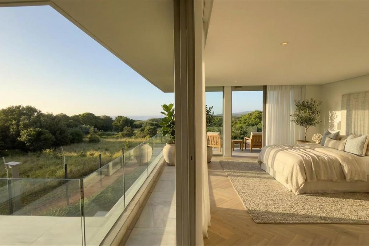 Spacious bedroom featuring herringbone timber flooring and large sliding glass doors opening onto a private balcony with scenic landscape views.