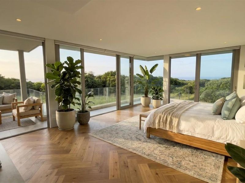Spacious bedroom featuring premium herringbone timber flooring, floor-to-ceiling sliding glass doors, and seamless access to a private balcony with scenic views.