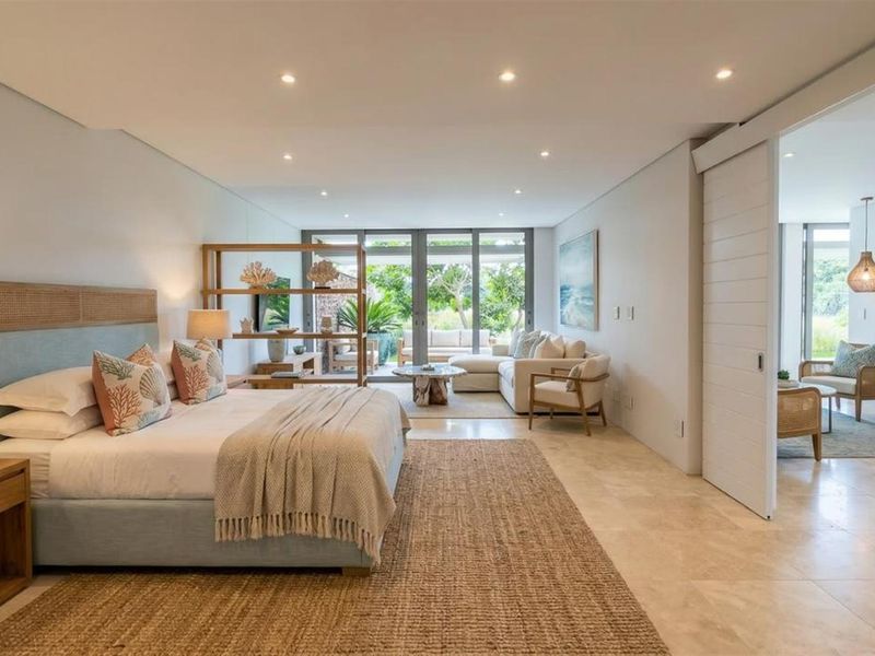 Spacious bedroom featuring stone flooring, recessed lighting, and large glass sliding doors leading to an outdoor area, with an adjacent room accessible via sliding door.