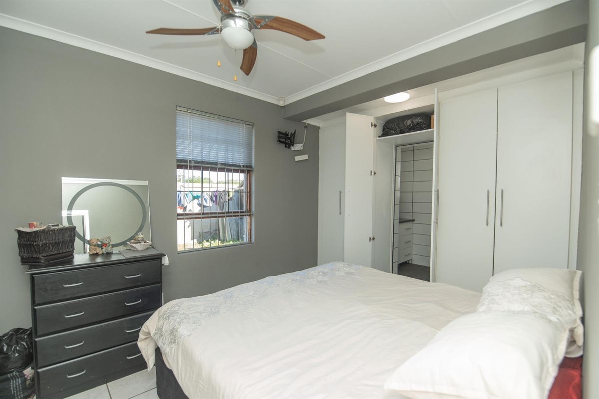A bedroom featuring built-in cupboards, a ceiling fan, and an attached walk-in closet area with tiled flooring.