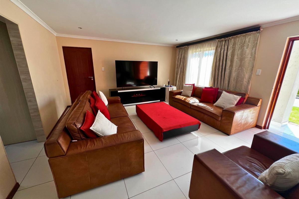 Spacious living room featuring large format floor tiles, recessed lighting, and direct access to the outdoor area through a sliding glass door.