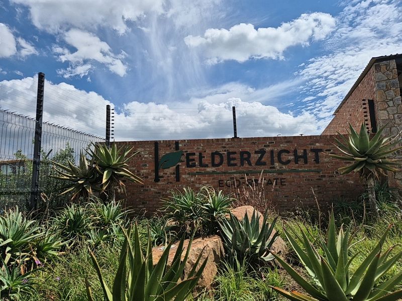 Entrance signage and brick boundary wall for Elderzicht Eco Estate, featuring electric fencing and established garden landscaping.