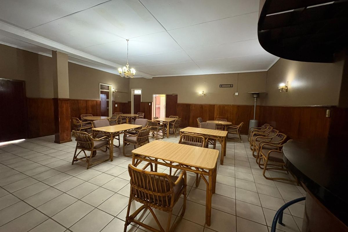 Spacious hotel dining or lounge area featuring tiled flooring and wood wall paneling, offering a functional layout for guests.