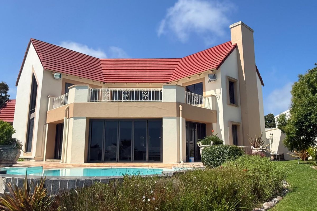 Rear view of a two-story residence featuring a swimming pool, a spacious balcony with metal railings, and large sliding glass doors.