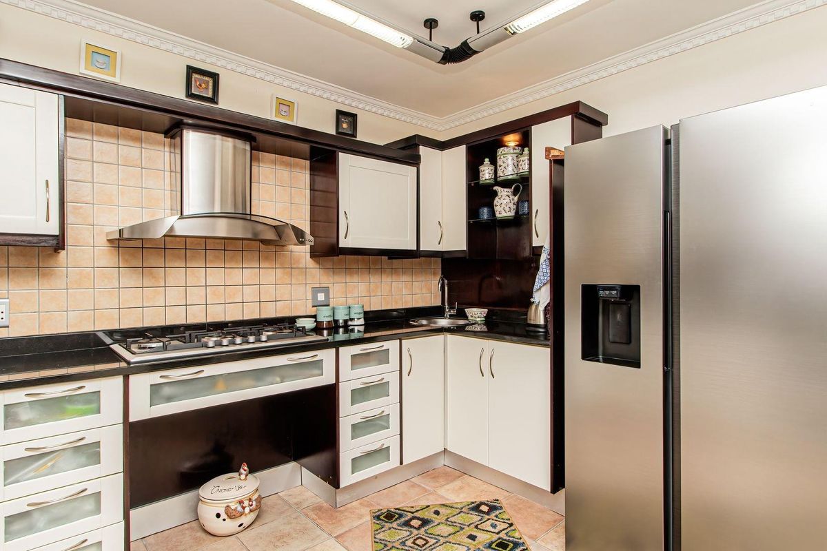 A well-maintained kitchen featuring dark and light cabinetry, granite countertops, a gas hob with extractor fan, and tiled backsplash.