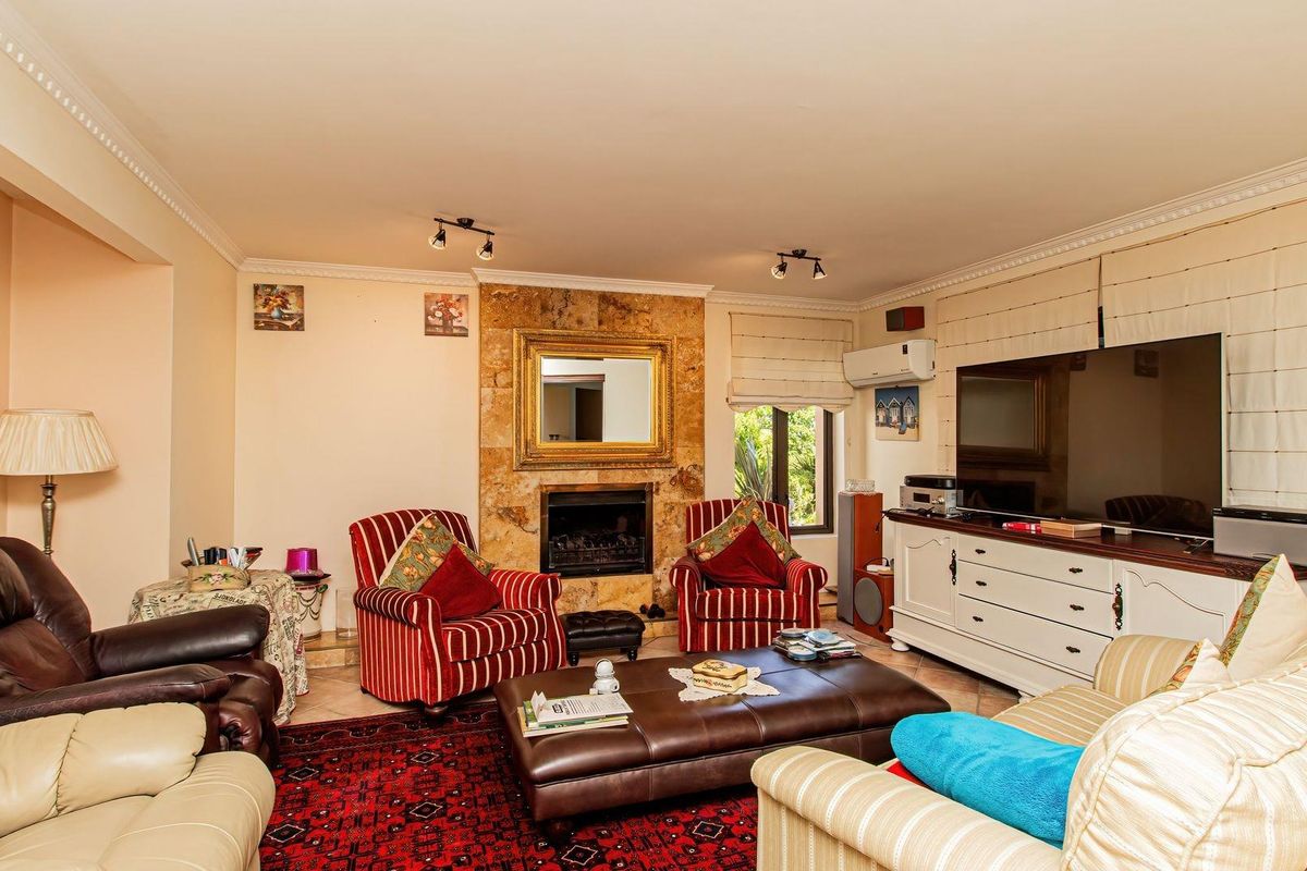 A comfortable living room featuring a stone-clad fireplace, crown molding, and split-system air conditioning, providing a functional and inviting space.