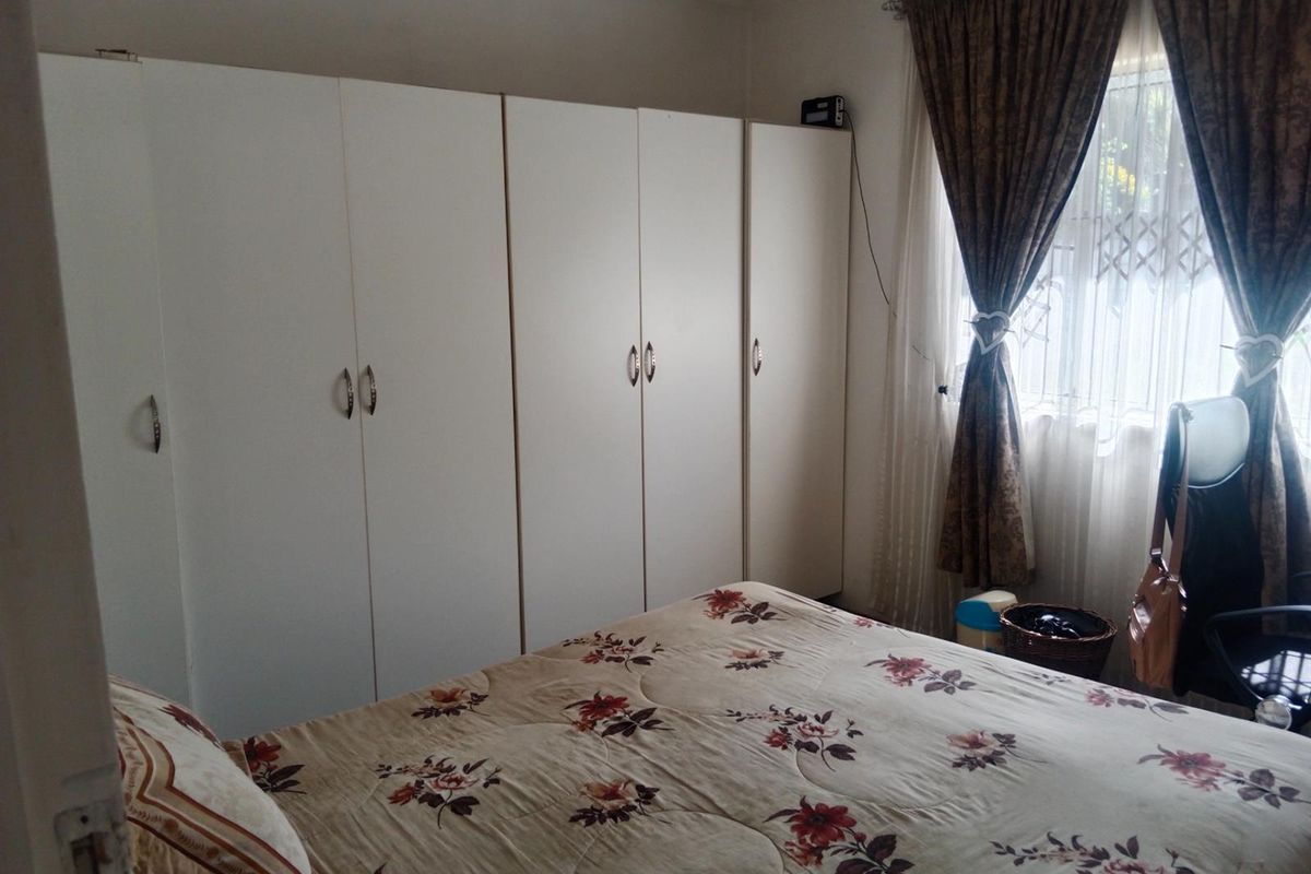 A bedroom featuring built-in white cabinetry and a window with curtains.