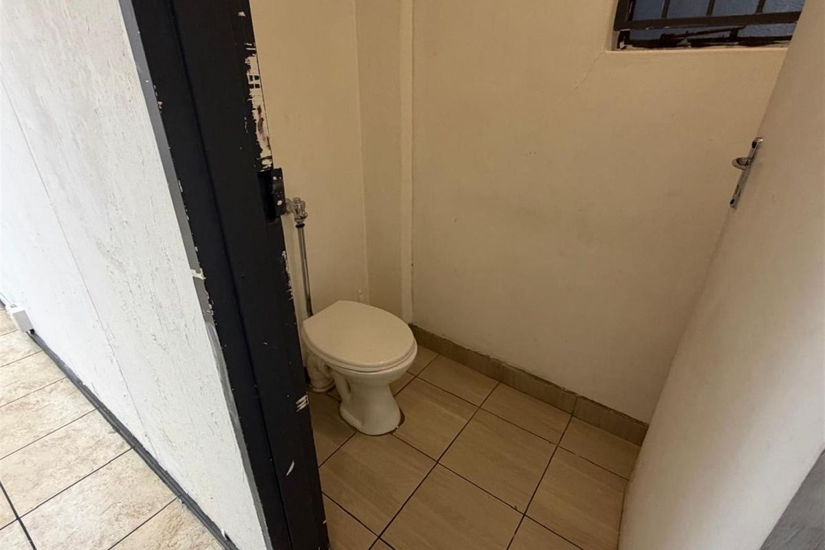 A compact, functional bathroom featuring tiled flooring and a standard toilet, requiring cosmetic updates to improve its overall condition.