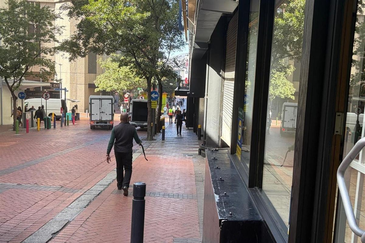A street-level view of the retail property exterior, featuring a paved pedestrian walkway and large display windows along the building facade.