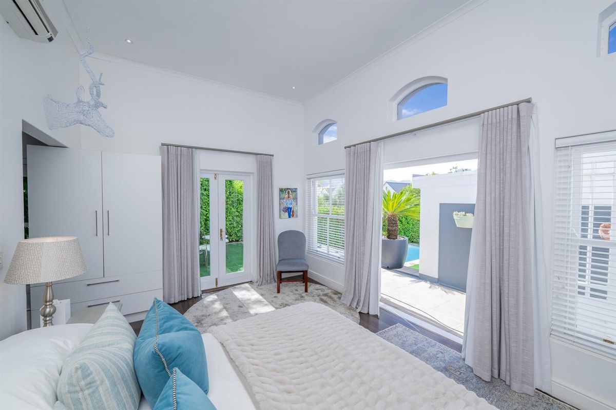 Bright and spacious bedroom featuring high ceilings, built-in cabinetry, and direct access to a private patio area through glass doors.