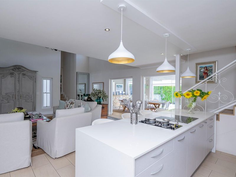 Spacious open-plan living area featuring a modern kitchen island with integrated cooktop, pendant lighting, and seamless flow to the dining and lounge spaces.