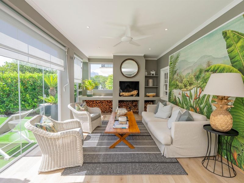 Bright and airy living room featuring a built-in fireplace, recessed shelving, ceiling fan, and large glass sliding doors opening to the garden.