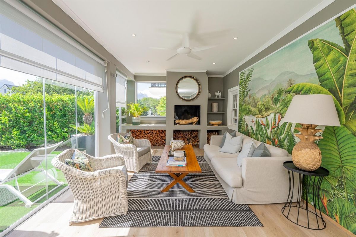 Bright and airy living room featuring a built-in fireplace, recessed shelving, ceiling fan, and large glass sliding doors opening to the garden.