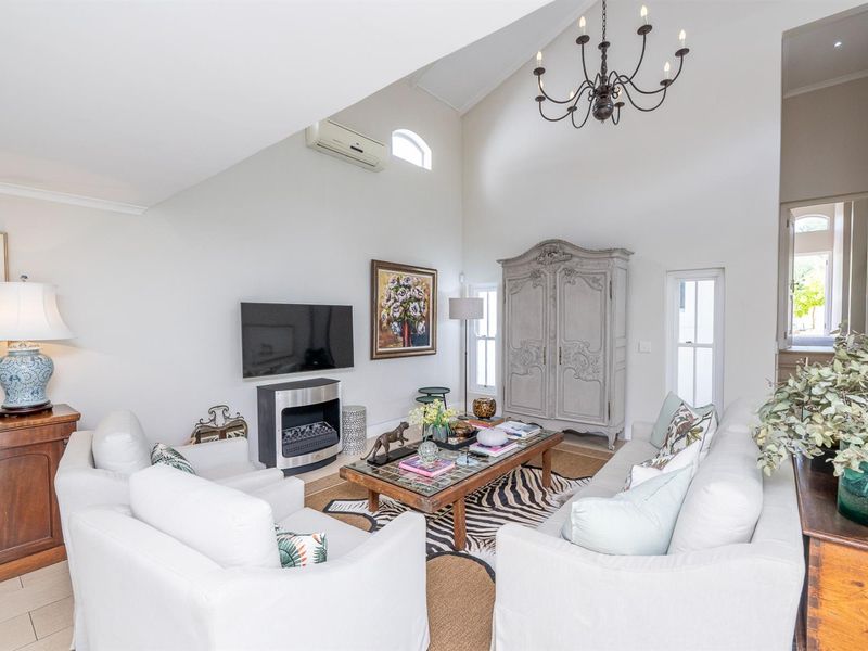 Spacious living room featuring a high vaulted ceiling, a classic chandelier, a built-in fireplace, and a wall-mounted air conditioning unit.