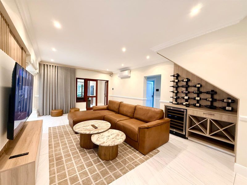A well-appointed living room featuring a custom built-in wine storage unit with integrated cooler, recessed lighting, and modern tiled flooring.