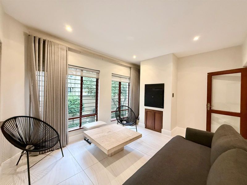 A bright living room featuring large windows with security bars, tiled flooring, recessed lighting, and built-in cabinetry.