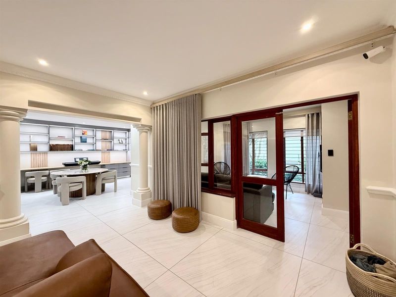 Spacious open-plan living area featuring elegant columns, built-in shelving, tiled flooring, and seamless transitions between the main living space and adjacent rooms.