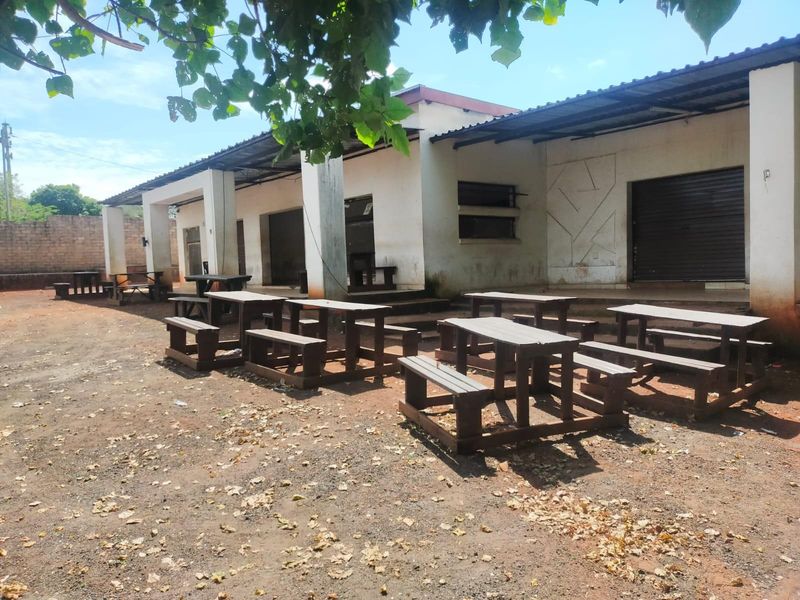 Rear exterior view of the business premises featuring a covered patio area, concrete pillars, and roller shutter access points.
