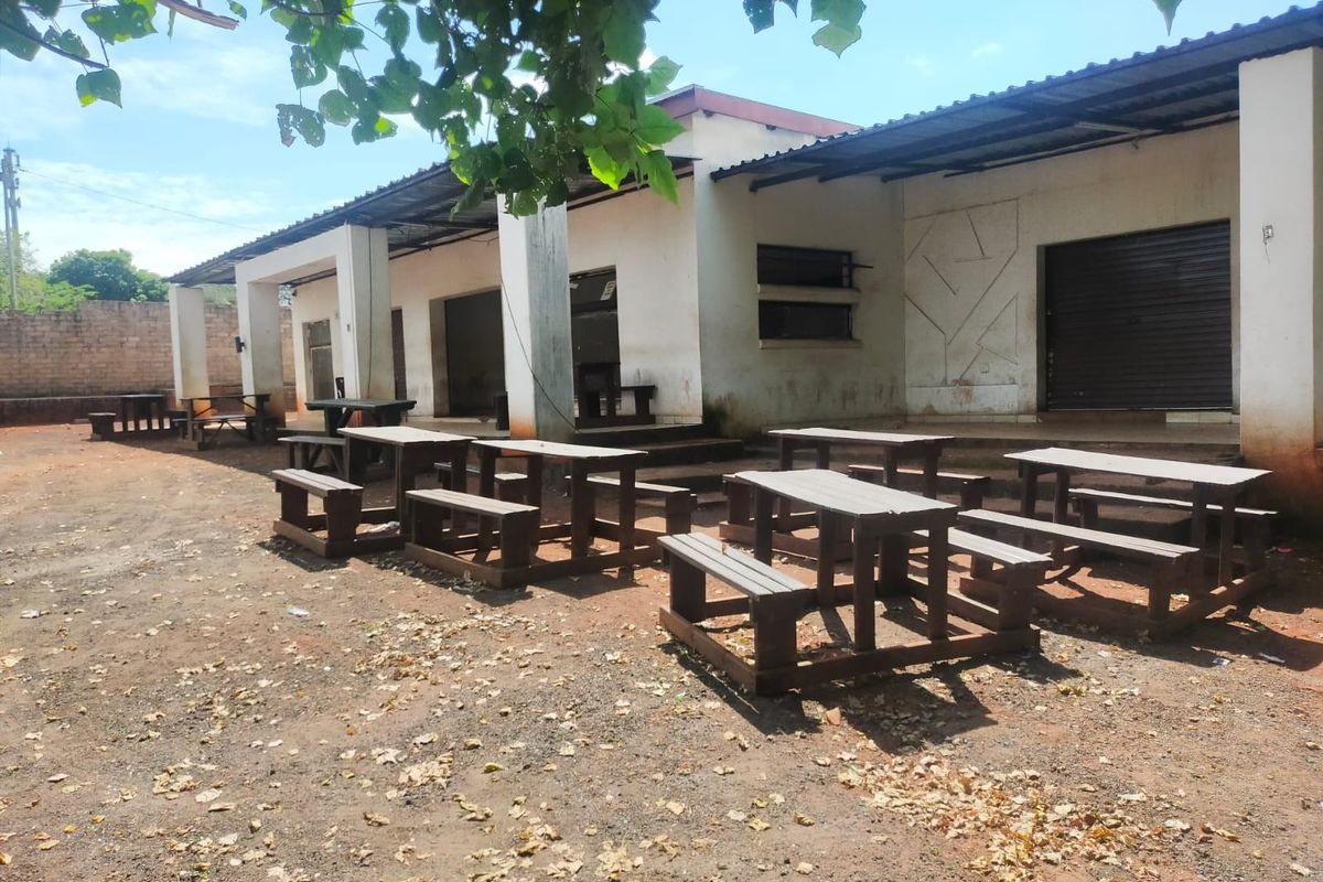 Rear exterior view of the business premises featuring a covered patio area, concrete pillars, and roller shutter access points.