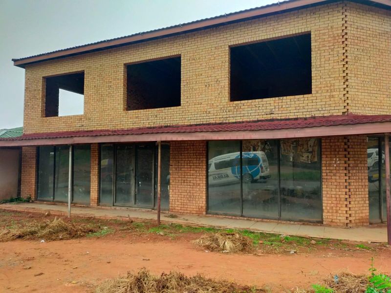 Two-story commercial building featuring a face brick facade, ground floor glass storefront, and unfinished upper-level window openings.