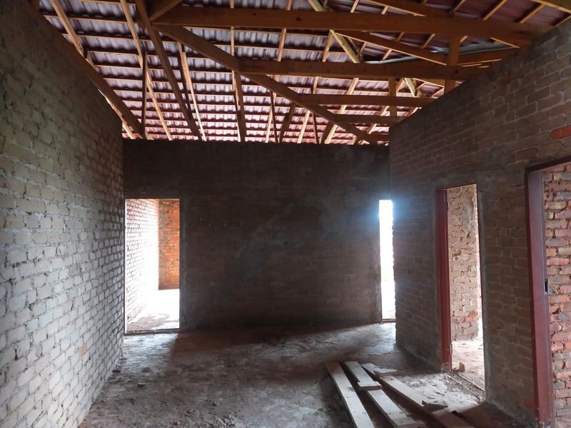 An interior view of a commercial property under construction, featuring exposed brick walls and timber roof trusses, awaiting final finishes and interior fit-out.