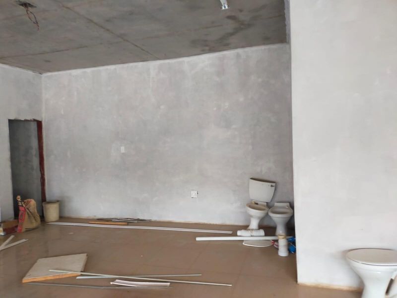 An unfinished bathroom space featuring exposed concrete ceilings, tiled flooring, and multiple toilets awaiting installation in a commercial property setting.