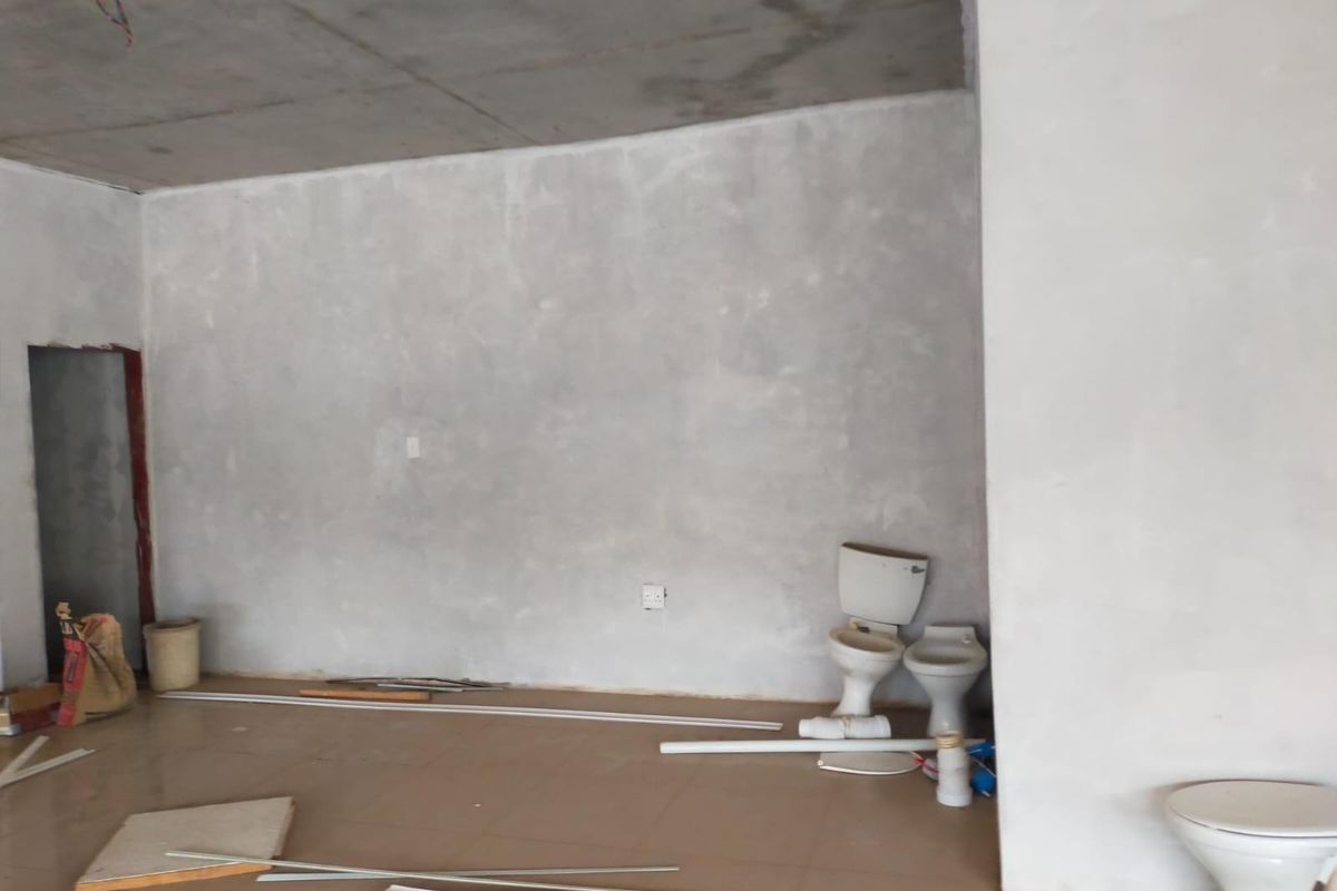 An unfinished bathroom space featuring exposed concrete ceilings, tiled flooring, and multiple toilets awaiting installation in a commercial property setting.