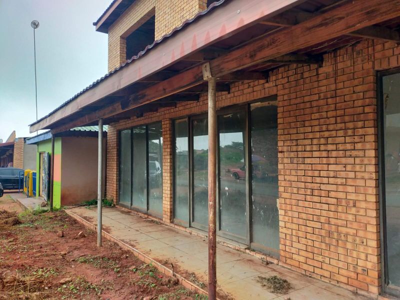 Commercial property exterior featuring a face brick facade, tiled veranda, and sliding glass doors with a timber roof structure.