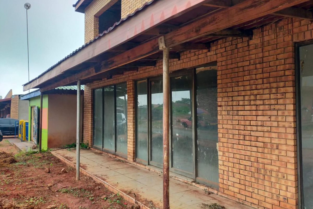 Commercial property exterior featuring a face brick facade, tiled veranda, and sliding glass doors with a timber roof structure.