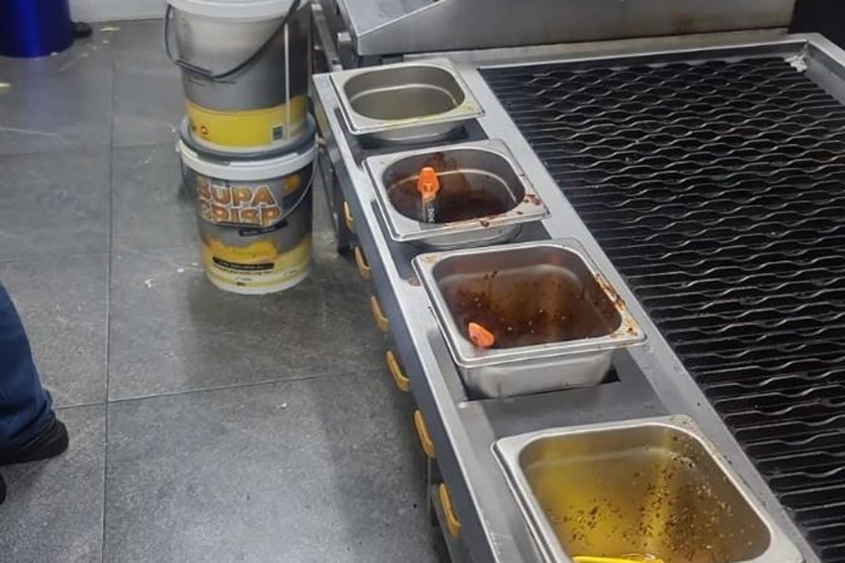 Commercial kitchen cooking station featuring a flat top grill, charbroiler, and stainless steel backsplash with tiled flooring.