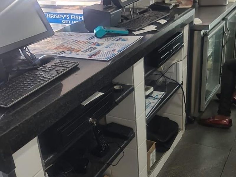 A functional restaurant service counter featuring a stone countertop, tiled base, and integrated under-counter refrigeration units for efficient food service operations.