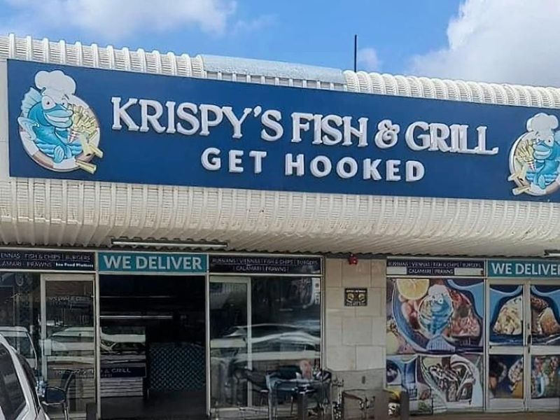 Front exterior view of Krispy's Fish & Grill restaurant featuring prominent signage, glass storefront, and paved parking area.