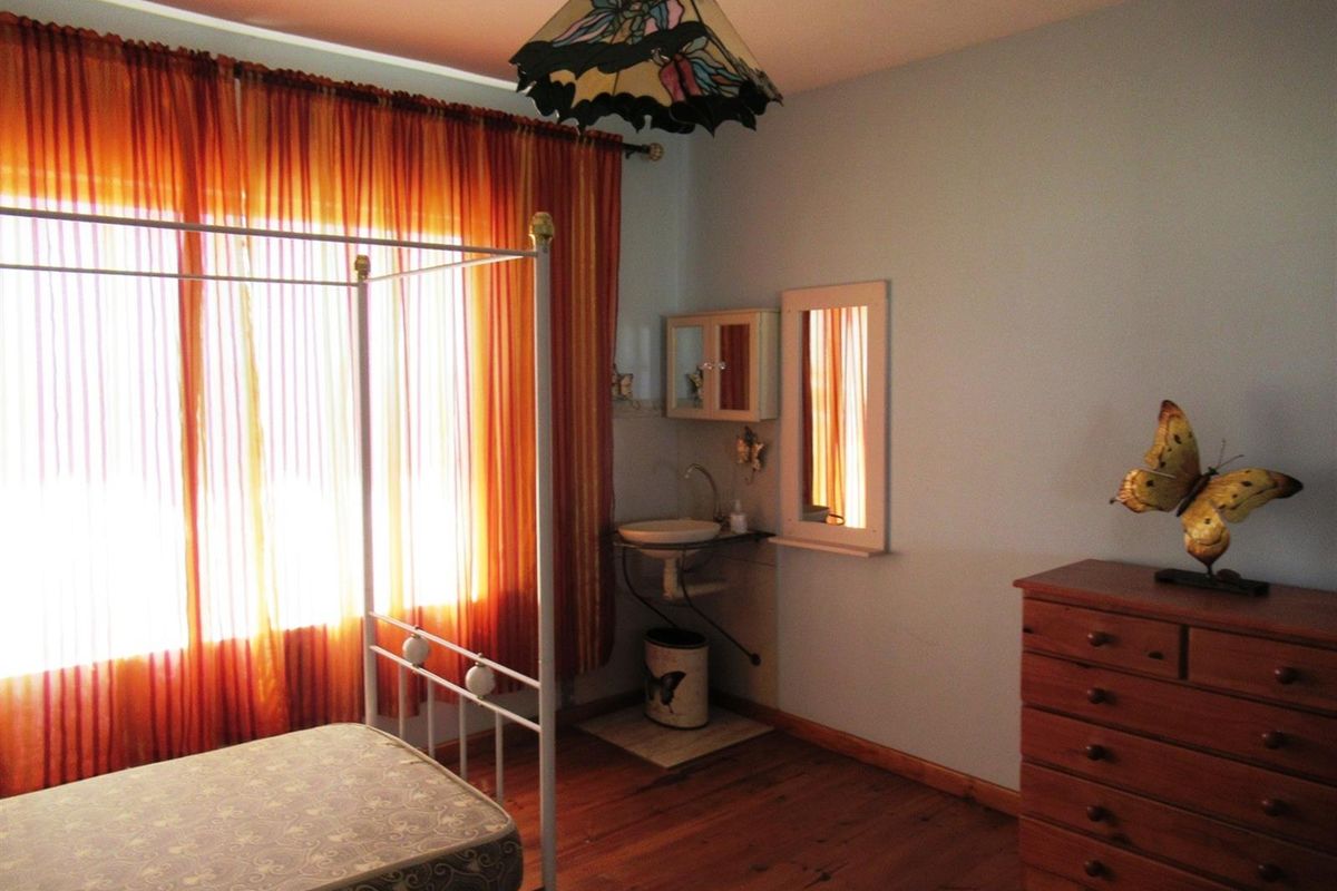 A bedroom featuring timber flooring and a built-in vanity basin with a wall-mounted mirror and cabinet.