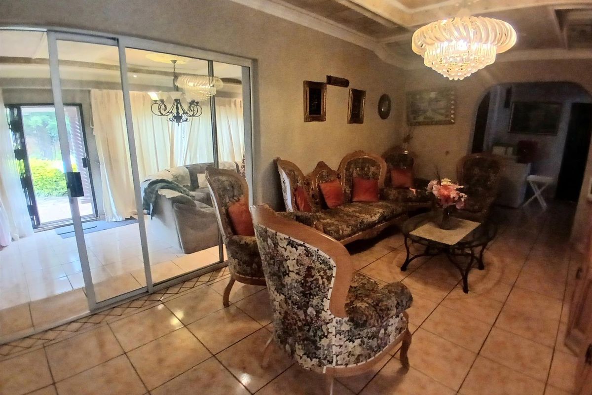 Spacious living room featuring tiled flooring, a recessed ceiling with decorative lighting, and large sliding glass doors providing access to the patio area.