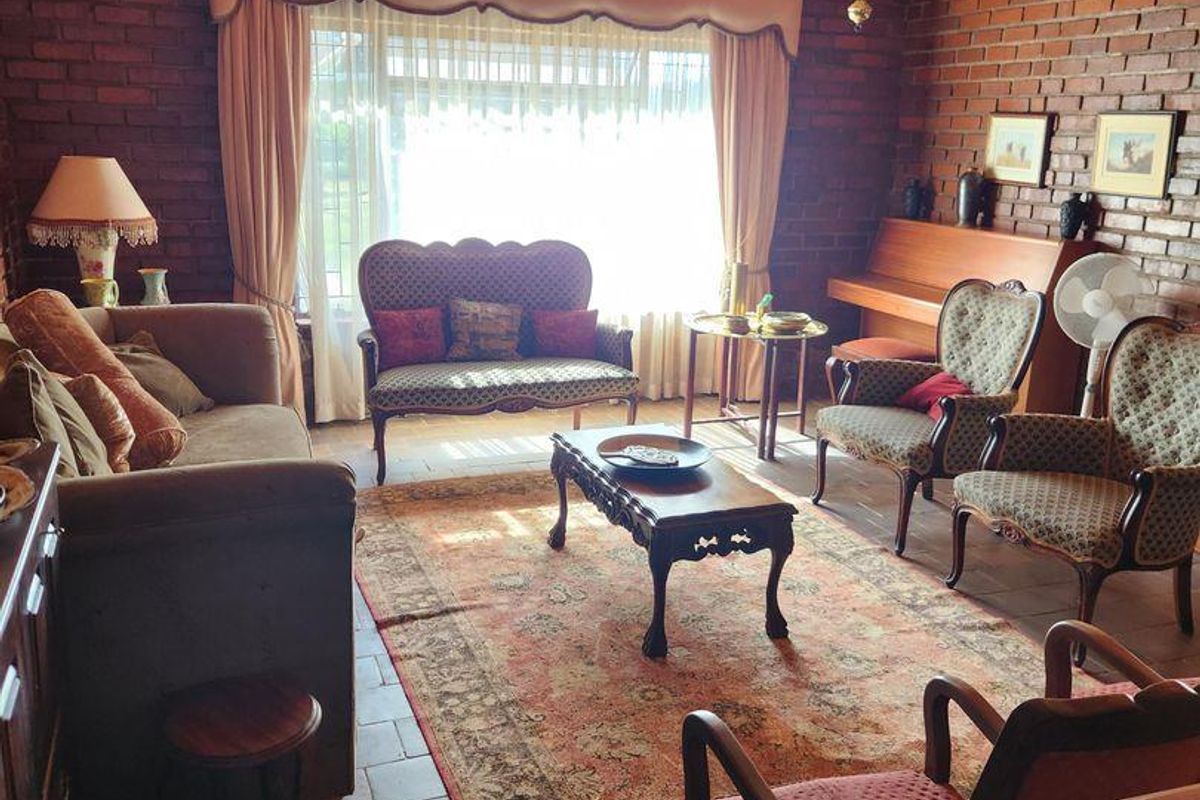 A rustic living room featuring exposed brick walls, a timber-clad ceiling, and terracotta tile flooring, creating a warm and traditional farm-style atmosphere.
