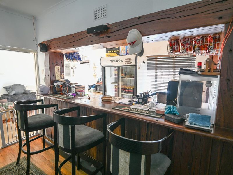 A rustic built-in timber bar area featuring a heavy wooden beam overhead and integrated counter space, suitable for entertaining.
