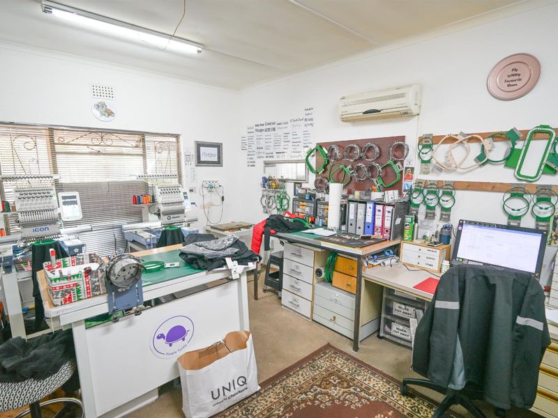 A functional utility space currently utilized as a workspace, featuring a wall-mounted air conditioning unit and fluorescent lighting.
