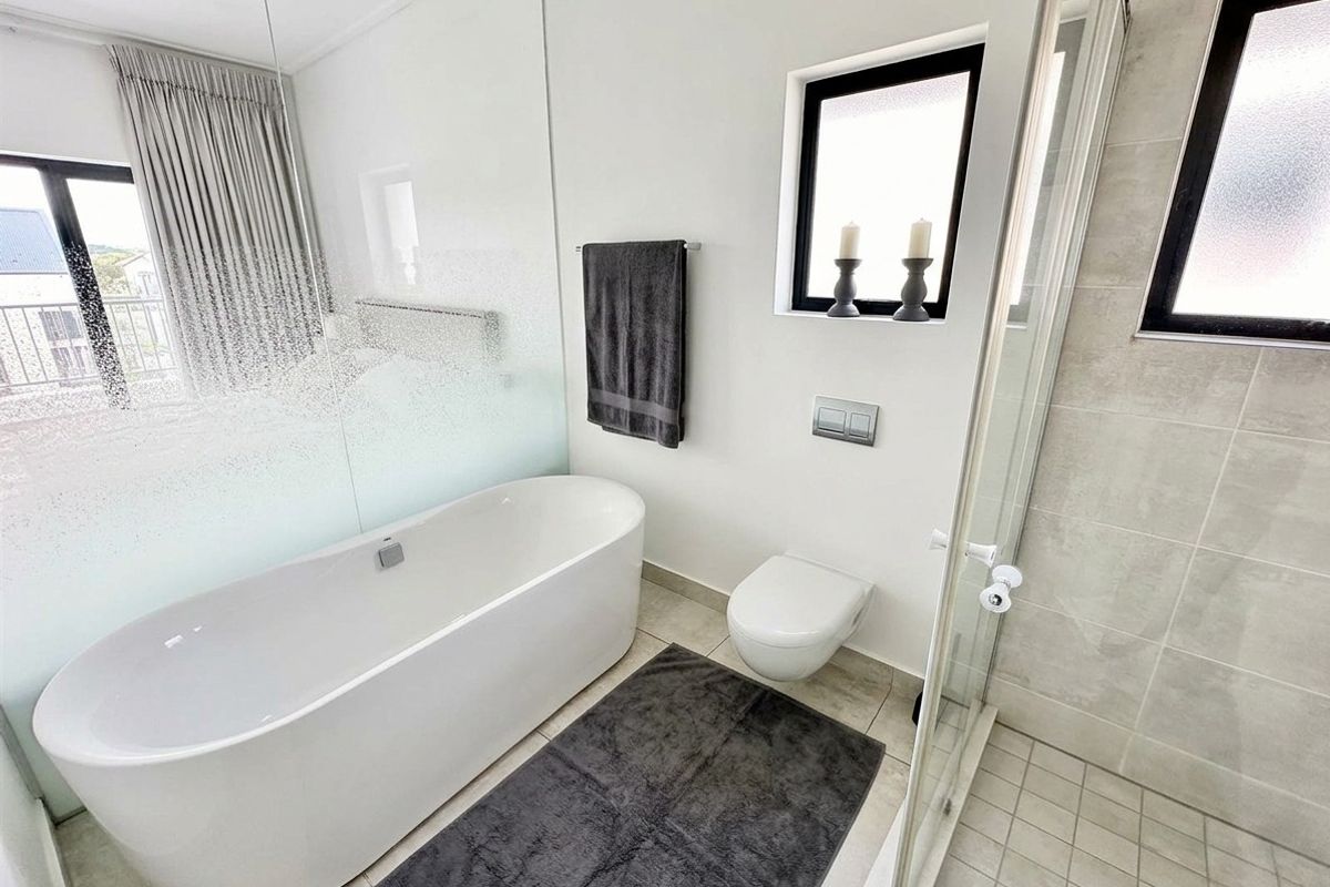 Modern bathroom featuring a sleek freestanding bathtub, wall-mounted toilet, and a glass-enclosed shower with contemporary tiled finishes.