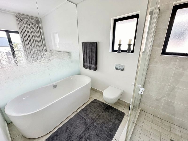 Modern bathroom featuring a sleek freestanding bathtub, wall-mounted toilet, and a glass-enclosed shower with contemporary tiled finishes.