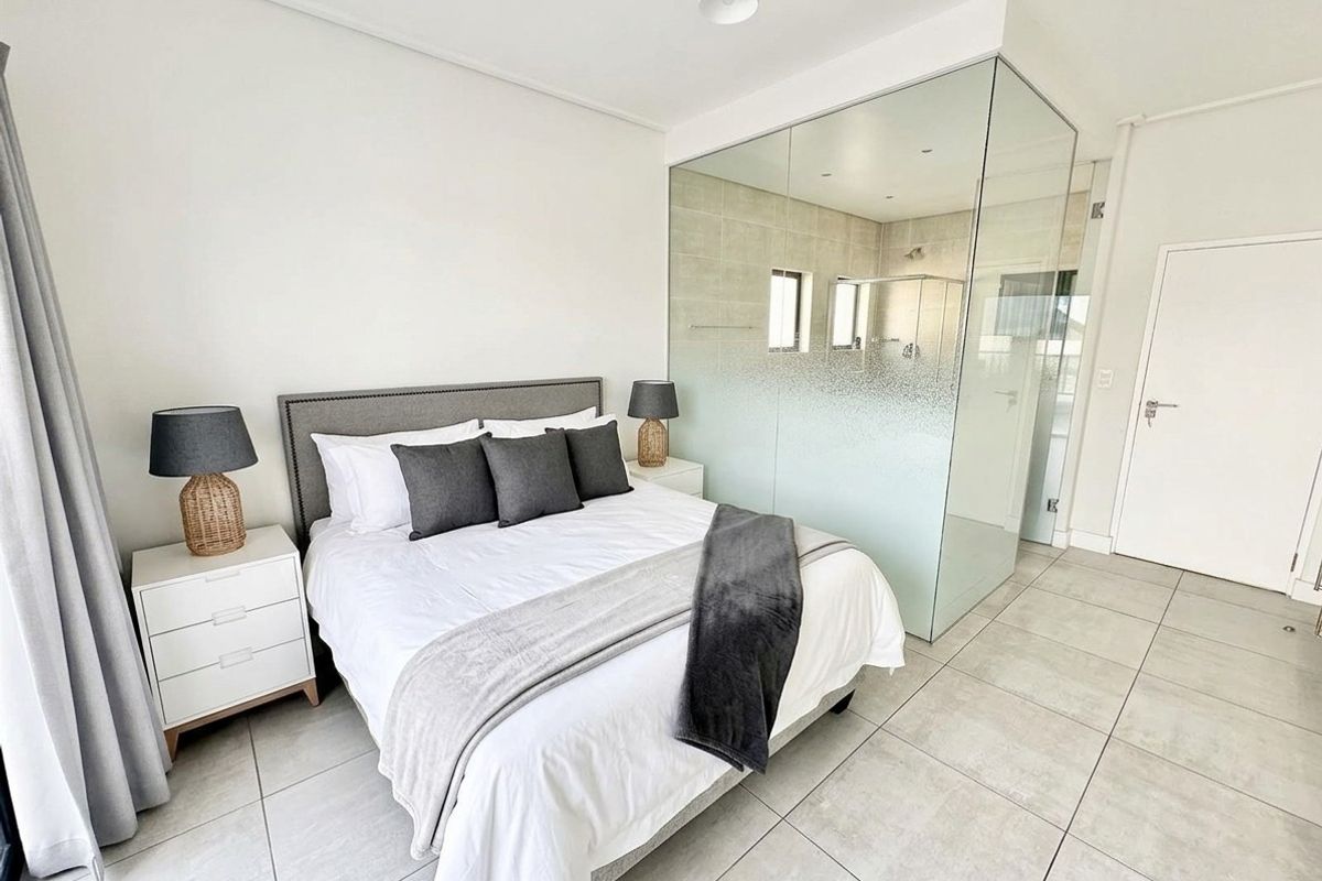 Modern bedroom featuring tiled flooring and a contemporary glass-enclosed en-suite bathroom with frosted privacy glass.