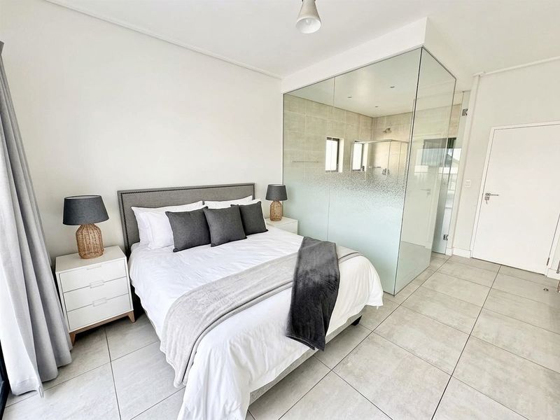 Modern bedroom featuring tiled flooring and a contemporary glass-enclosed en-suite bathroom with frosted privacy glass.