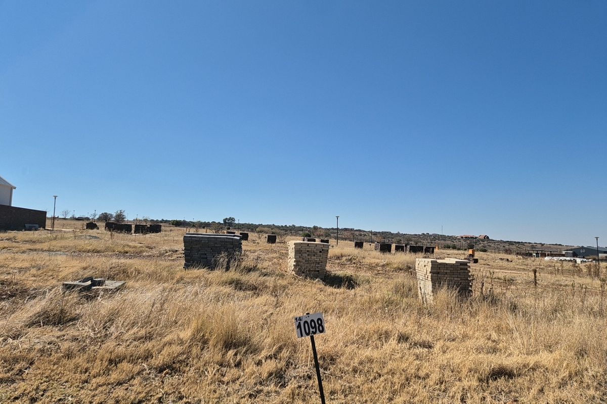 A view of a vacant residential plot featuring dry grass and site markers, ready for development.