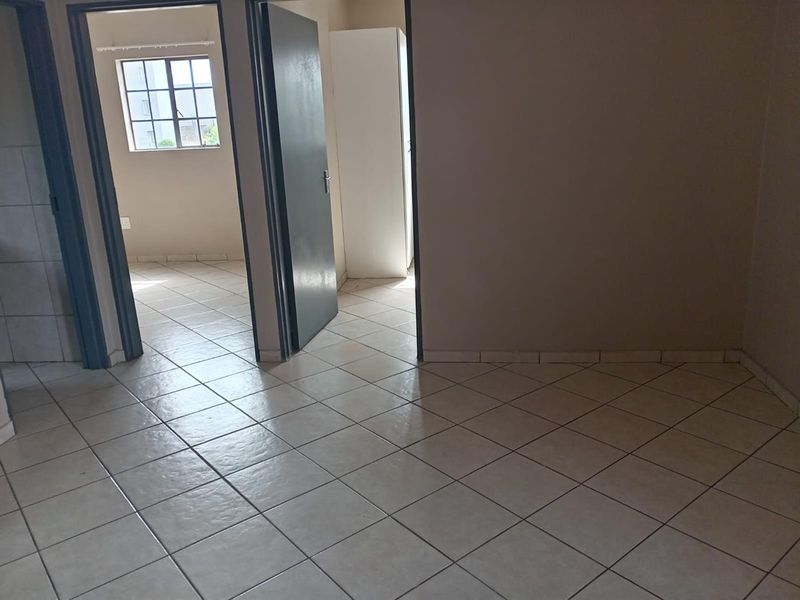 A vacant hallway area featuring neutral tiled flooring and access to adjacent rooms through internal doorways.