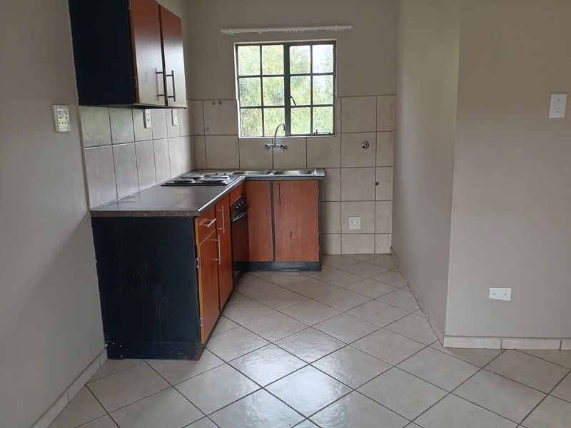 A functional kitchen featuring built-in cabinetry, laminate countertops, a stainless steel sink, and tiled flooring, offering a clean and practical workspace.